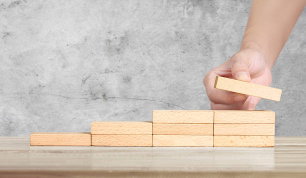istock Hand liken person stepping up wood block stacking as step stair 1184742302