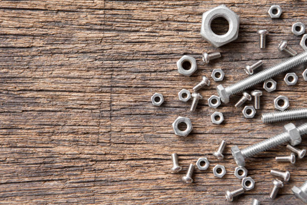 Top view of Many nuts and bolts on wood background and copy space Top view of Many nuts and bolts on wood background and copy space nut fastener stock pictures, royalty-free photos & images