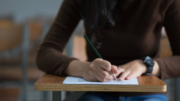 istock Young female university student concentrate doing  examination in classroom. Girl student writes the exercise of the examinations. University examination and education concept. 1184750448