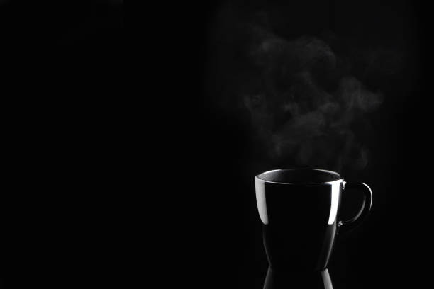 istock steaming coffee or tea in black mug with reflection on dark background 1184752493