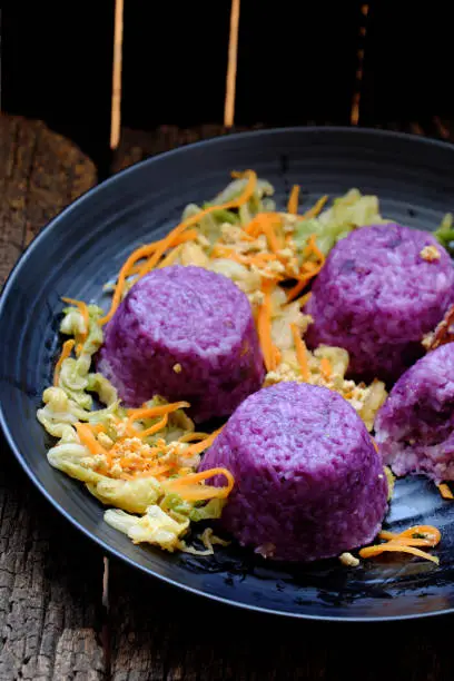 Vietnamese homemade vegetarian eating on black plate, violet rice dish with vegetables, delicious vegan meal that frugal, healthy