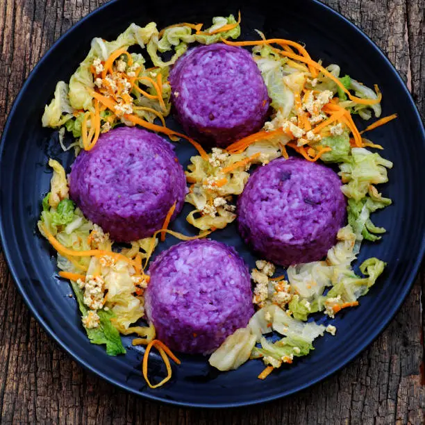 Vietnamese homemade vegetarian eating on black plate, violet rice dish with vegetables, delicious vegan meal that frugal, healthy