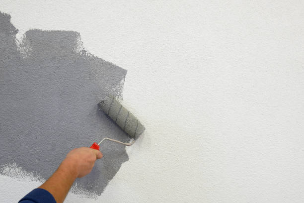 istock painting walls with a roller in his left hand. 1184780466