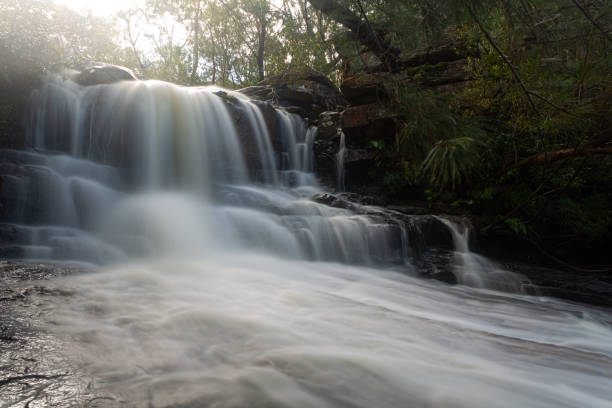 istock Beautiful fast flowing waterfall flowing over rock ledge and 1184784747