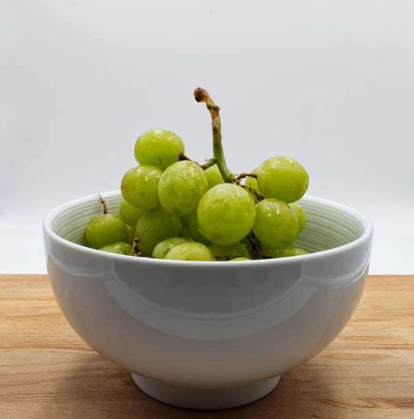 istock Green grape in a jar on wooden table, white background 1184786881