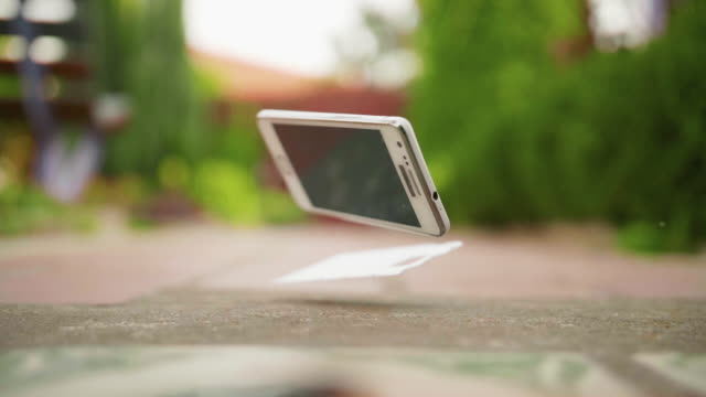 Mobile phone falls and breaks on the concrete ground in slow motion