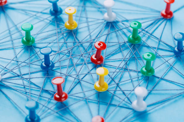 istock Small network of pins (Thumbtack)and string, An arrangement of colorful pins linked together with string on a pale blue background suggesting a network of connections. 1184787582