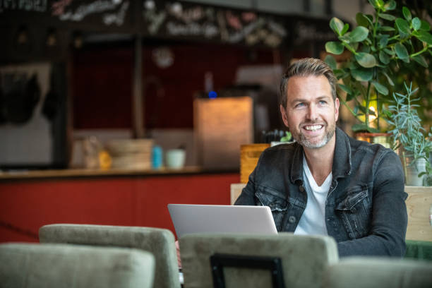 man working on his laptop in a bar - dutch ethnicity imagens e fotografias de stock