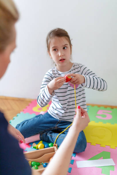 istock Girl practicing fine motor skills looking at her tutor 1184790758