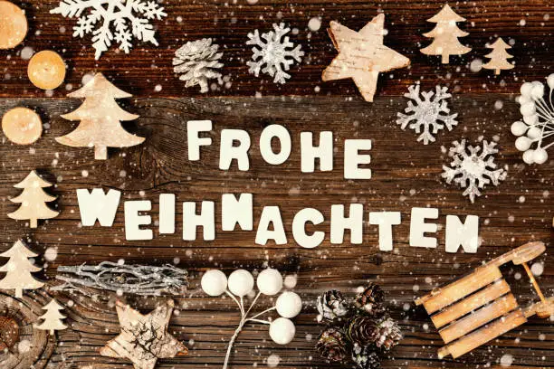 Letters Building The Word Frohe Weihnachten Means Merry Christmas. Wooden Christmas Decoration Like Tree, Sled And Star. Brown Wooden Background With Snowflakes