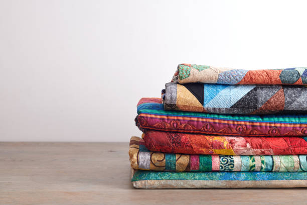 istock Quilts stacked on wooden table on white wall background 1184793299