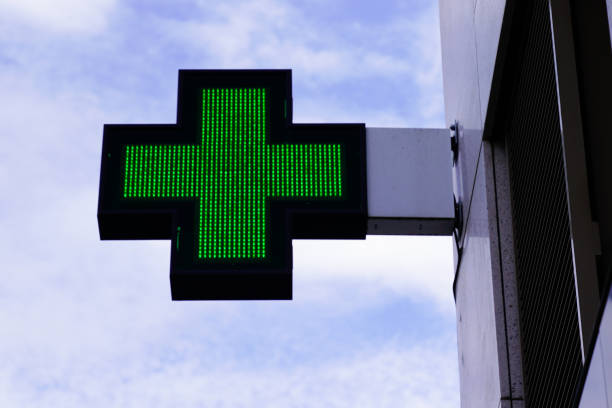 green cross pharmacy sign in street - green cross imagens e fotografias de stock