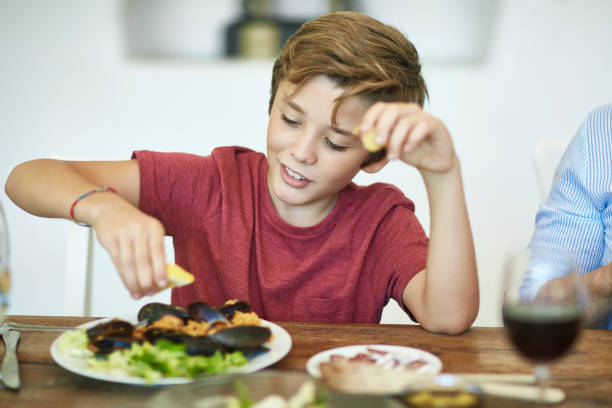 istock Hungry Young Boy Squeezing Lemon on Mussels in Paella 1184807877