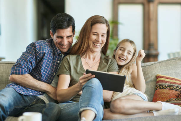 istock Laughing Young Spanish Family on Sofa Using Digital Tablet 1184807882