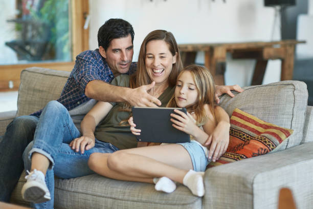 istock Young Spanish Family Together on Sofa Using Digital Tablet 1184807892