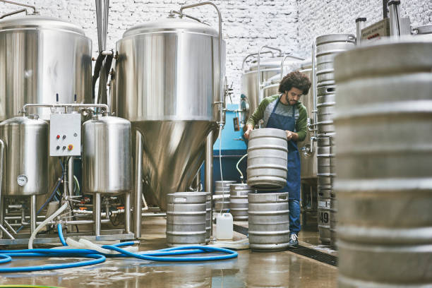 istock Male Craft Brewery Worker Stacking Kegs for Washing 1184808112