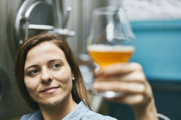 istock Smiling Female Craft Brewer Checking Beer Sample for Clarity 1184808121
