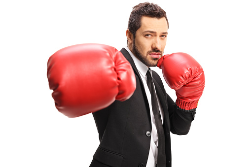 Businessman punching with red boxing gloves isolated on white background