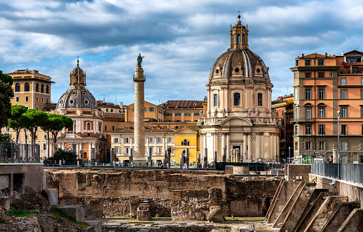 Cityscape of old town Rome, with traditional buildings, domes and towers, and view of archaeological dig in famous Piazza Venezia.