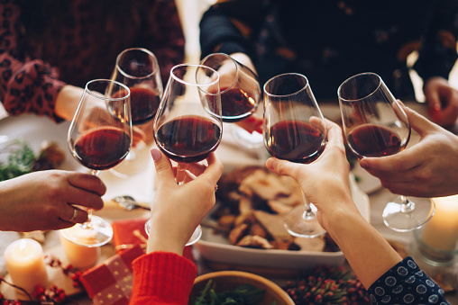 Friends clinking glasses with red wine at the dinner party