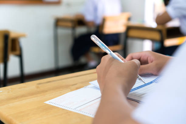 istock English exams test student in school, university students holding pencil for testing exam writing answer sheet or exercise for taking in assessment paper on table classroom. Education study Concept 1184820645