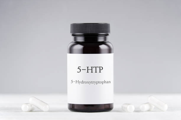 integratore alimentare 5-htp idrossitriptofano, bottiglia e capsule su grigio - herbal medicine flash foto e immagini stock