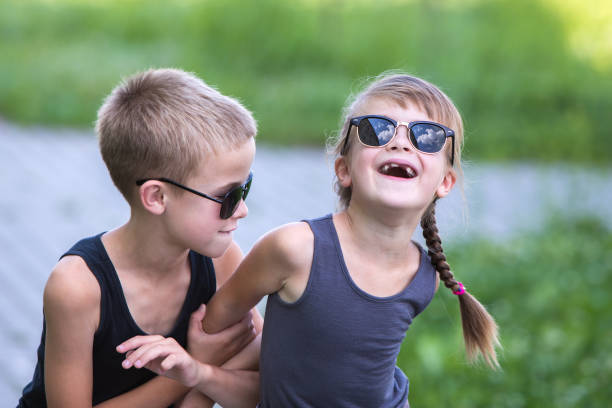 istock Two children in black sunglasses having fun time outdoors in summer. 1184825150