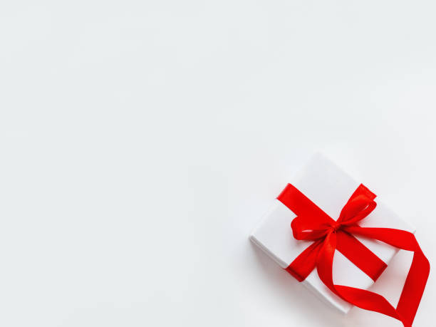 istock Present in white wrapping paper on white backdrop. Holiday gift with red ribbon and bow. Copy space. 1184828234