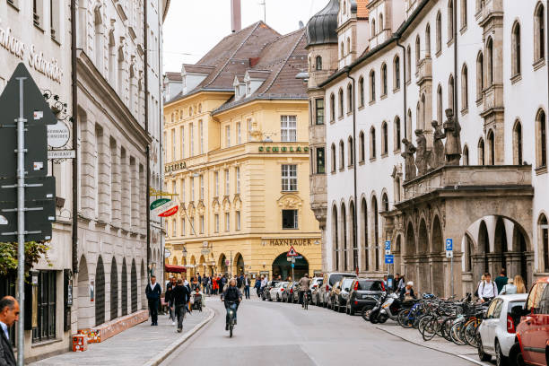 People passing through Sparkassenstrasse in Munich. Stadtsparkasse building on the right, Akademischer Gesangverein on the background.