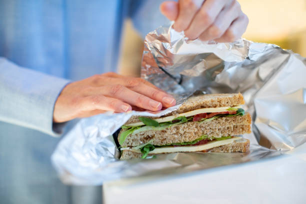 крупным планом женщина упаковка сэндвич в неразовые алюминиевой фольги - wrap бутерброд стоковые фото и изображения
