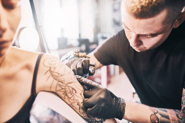 istock Tattoo Artist making a tattoo on a customer's shoulder 1184829038