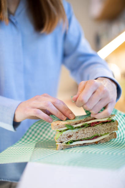 Close Up Of Woman Wrapping Sandwich In Reusable Environmentally Friendly Beeswax Wrap Close Up Of Woman Wrapping Sandwich In Reusable Environmentally Friendly Beeswax Wrap beeswax wrap stock pictures, royalty-free photos & images