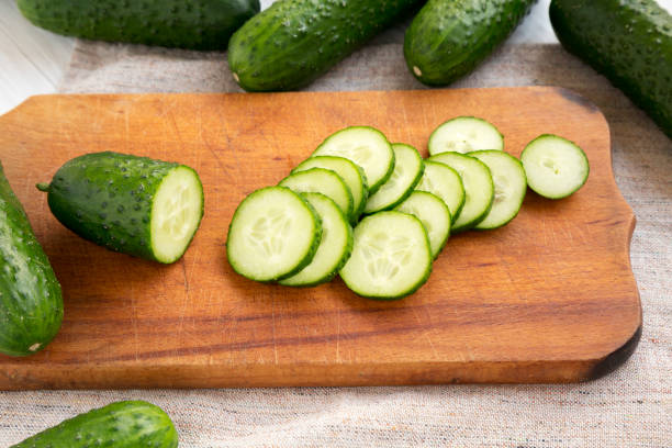 istock Fresh mini baby cucumbers on a rustic wooden board, low angle view. Closeup. 1184829279