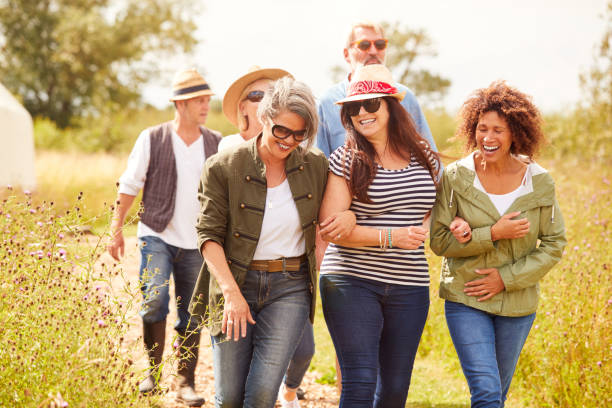 group of mature friends walking along path through yurt campsite - walking exercising relaxation exercise group of people imagens e fotografias de stock