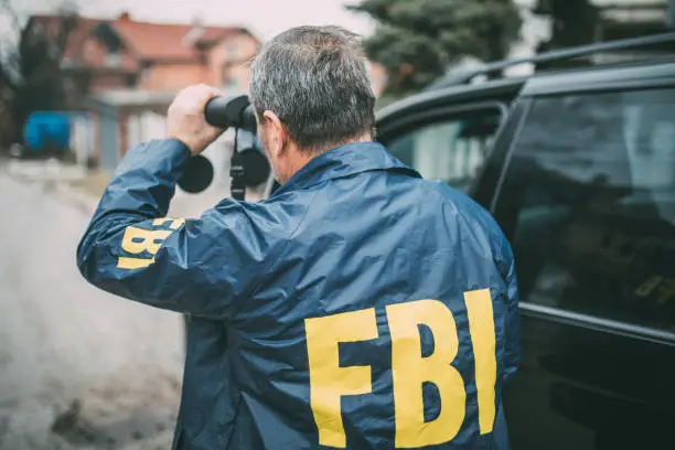 An old FBI agent uses binoculars