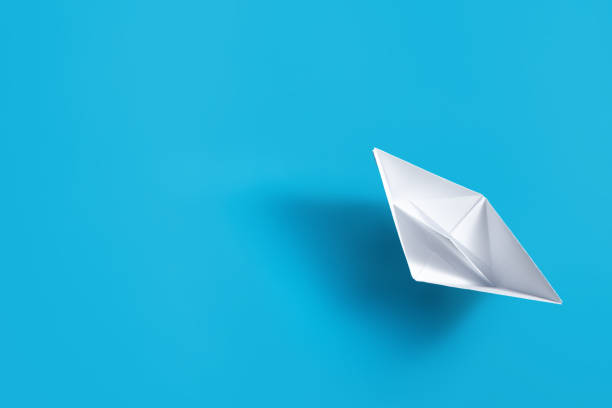 istock White paper boat on blue background. 1184835113