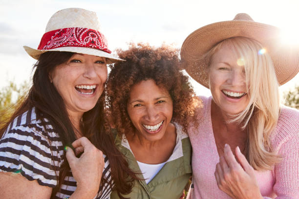 verticale des amis féminins mûrs marchant par le domaine sur des vacances de camping - friendship senior adult caucasian cheerful photos et images de collection