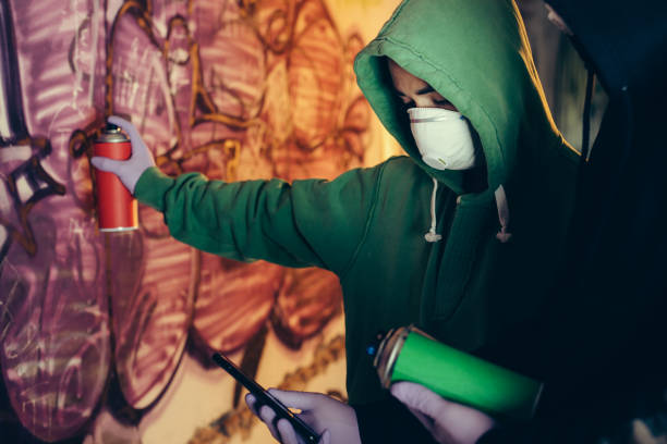 A young graffiti artist pointing a spray can at the camera.