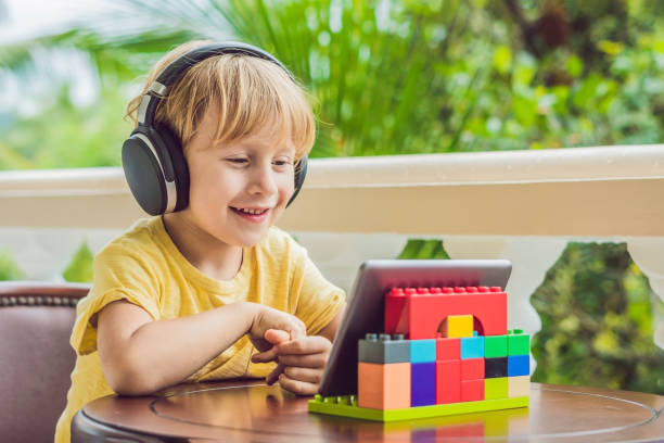 niño en los trópicos hablando con amigos y familiares en videollamada utilizando una tableta y auriculares inalámbricos - nativo digital fotografías e imágenes de stock