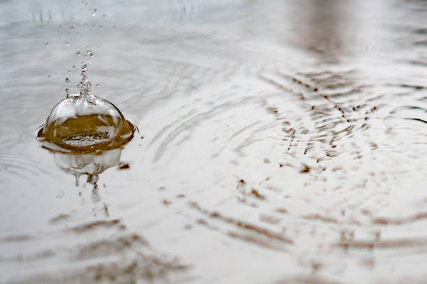 istock Splash water from rain droplets on wet ground 1184847377