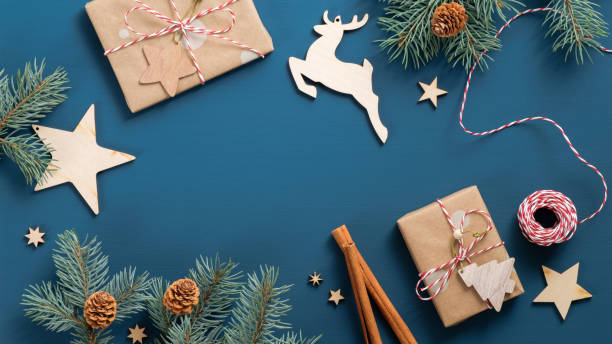 istock Christmas greeting card with fir tree branches, cinnamon sticks, gift boxes wrapped craft paper, vintage wooden decoration, striped rope on dark blue background. Xmas banner mockup, postcard template 1184848593