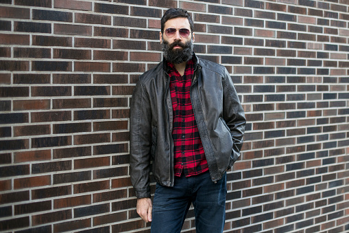 Mid adult man in plaid shirt, leather jacket and aviator sunglasses. About 35 years old, Caucasian male with beard.