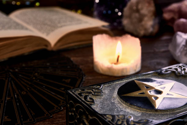 古い木製のテーブルトップ、黒い占い師カード、魔法の本とペンタグラムの箱に燃えるろうそくと静物。魔法や難解に適しています。