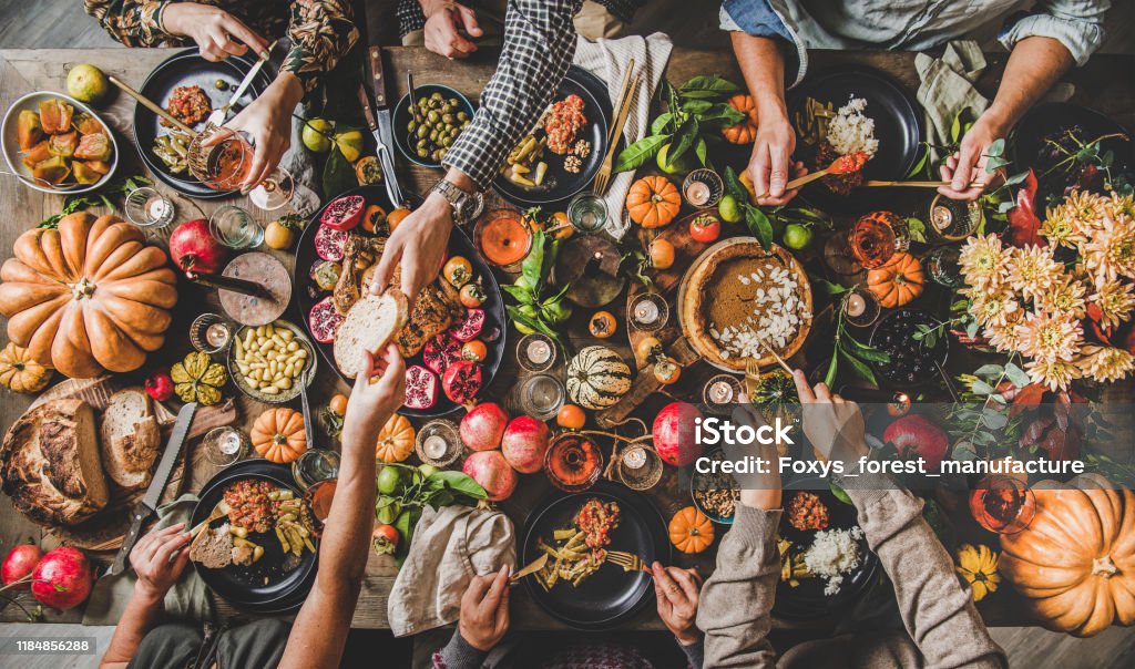 People eating and drinking wine at Thanksgiving celebration dinner table Family celebrating Thanksgiving day. Flat-lay of eating and drinking peoples hands over Friendsgiving table with traditional Fall food, roasted turkey, candles, pumpkin pie, top view Thanksgiving - Holiday Stock Photo People eating and drinking wine at Thanksgiving celebration dinner table Family celebrating Thanksgiving day. Flat-lay of eating and drinking peoples hands over Friendsgiving table with traditional Fall food, roasted turkey, candles, pumpkin pie, top view Thanksgiving - Holiday Stock Photo