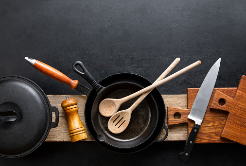 Kitchen utensils dark background with cast iron black kitchenware, top down view, blank space for a text