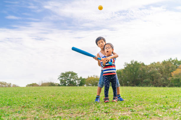 due bambini che giocano a baseball - baseballs baseball grass sky foto e immagini stock