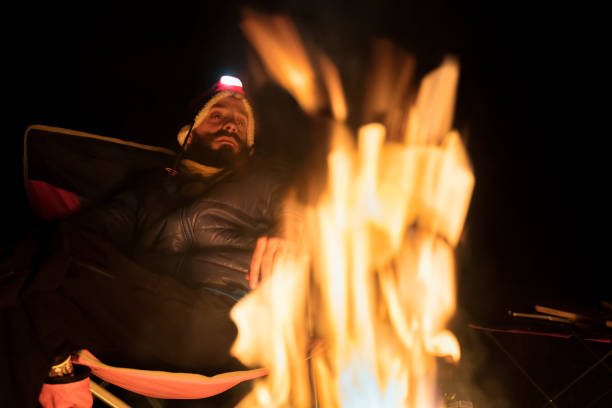 istock Man warming up with campfire in woods 1184871736