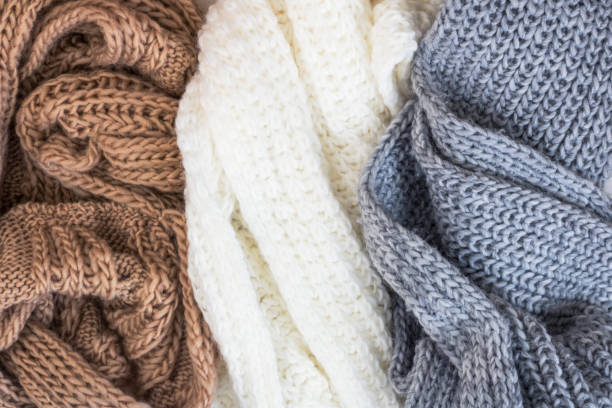 Dziane swetry z frędzlami w odcieniach brązu, bieli i szarości, idealne do stylizacji.