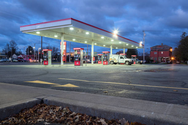 Industrial standard big rigs semi trucks with semi trailers standing on the fuel station parking lot filling the semi trucks tanks with diesel fuel to have ability continue commercial flight