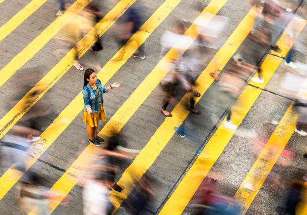 Peace in the city A woman has a moment of peace and calm on a crowded crosswalk in Hong Kong. The crowds crossing the street are blurred by a long exposure. defocused woman stock pictures, royalty-free photos & images